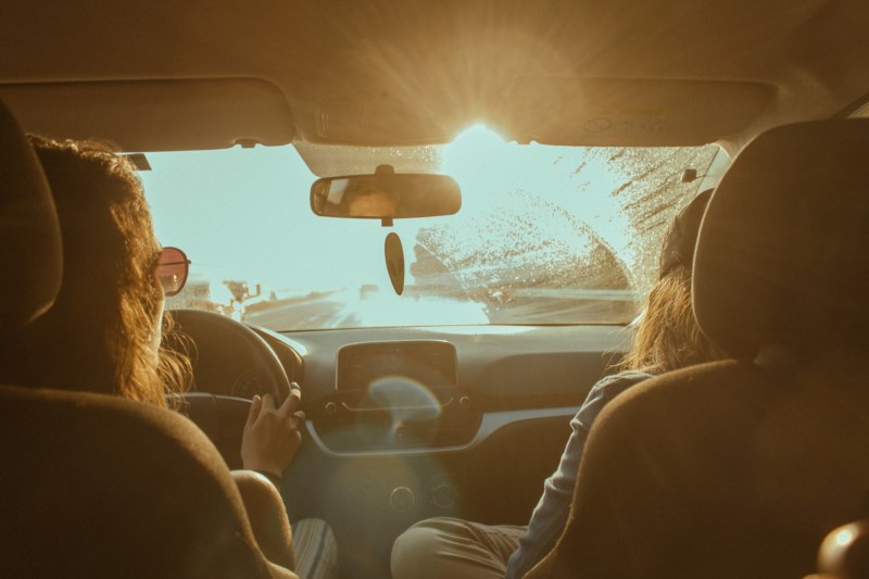 To jenter kjører bil med lav høstsol