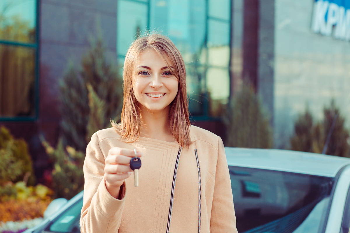 En ung kvinne holder en bilnøkkel i hånden